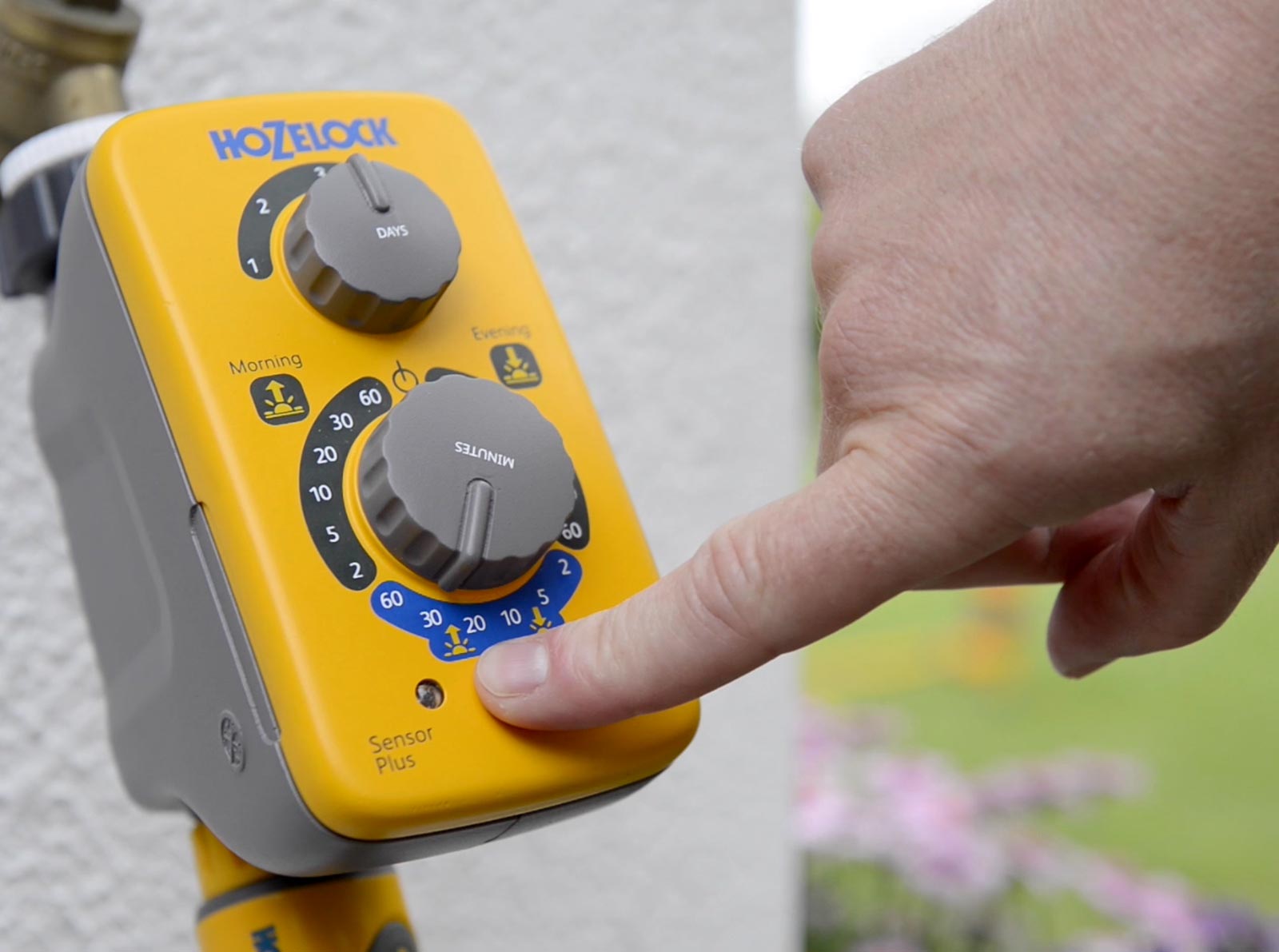 Image of a person pressing the water now button on the Hozelock Sensor plus controller
